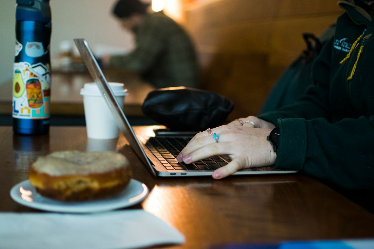 Person jobber med laptop ved trebord