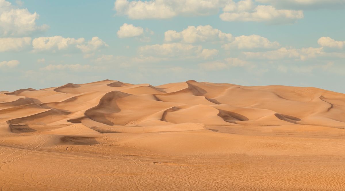 Sanddyner under bla himmel ved Dubai