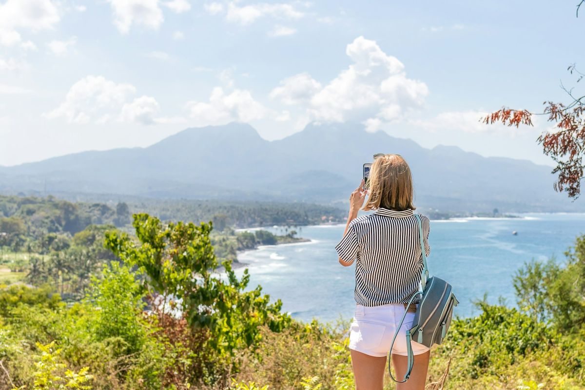 Kvinne fotograferer kysten med mobiltelefonen på reise