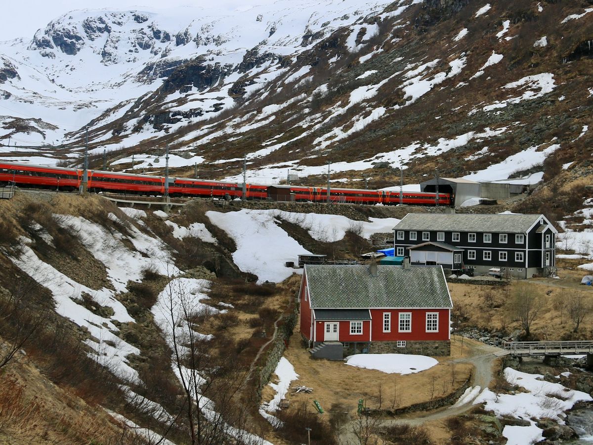 Rodt tog langs snodekt fjell i Norge